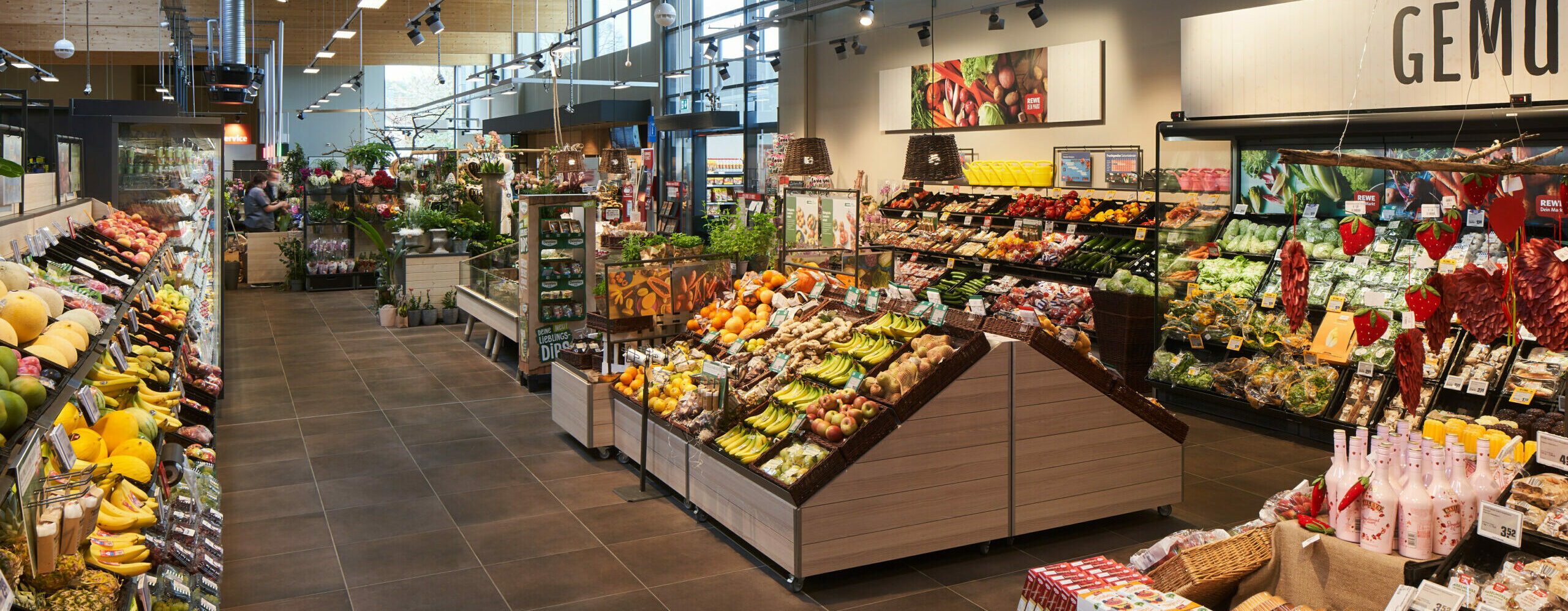 Wareninsel mit einem Schild, dass auf regionale Ware hinweist. Auf der Wareninsel sind Kisten mit Gemüse, darunter zum Beispiel Kohlrabi, Tomaten, Karotten, Salatköpfe und Gurken.