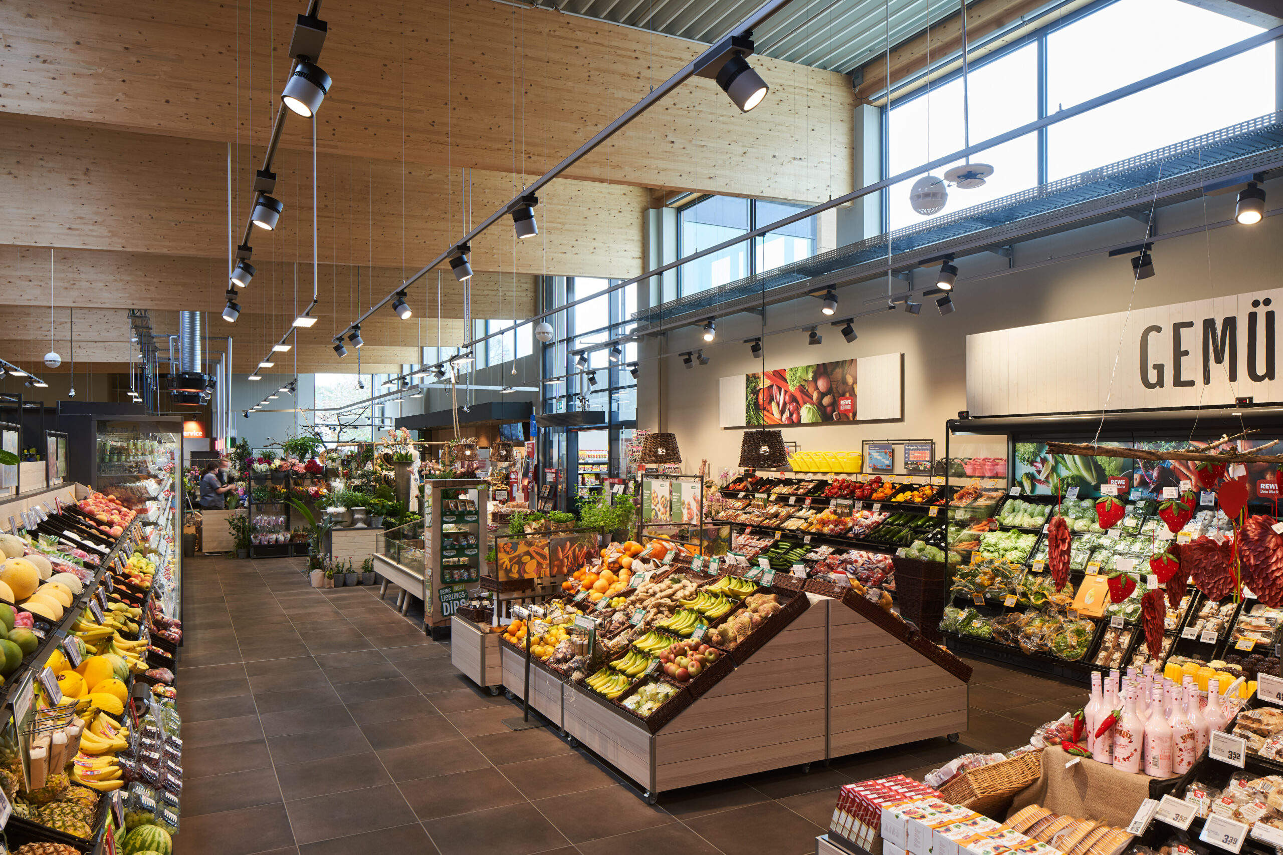 Wareninsel mit einem Schild, dass auf regionale Ware hinweist. Auf der Wareninsel sind Kisten mit Gemüse, darunter zum Beispiel Kohlrabi, Tomaten, Karotten, Salatköpfe und Gurken.